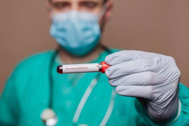 Cerrah elinde kovid 19 test tüpü tutuyor.
