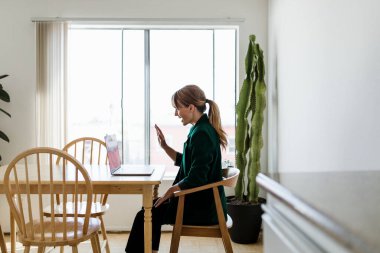 Coronavirus salgını sırasında evden çalışan neşeli bir kadın.