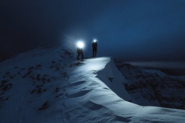 İskoçya 'nın Liathach Sırtı' ndaki soğuk gecede dağcılar yürüyüş yapıyor.