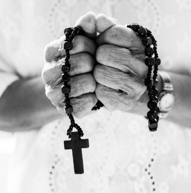 Siyah ve beyaz haçla dua eden elleri birbirine kenetleyin.