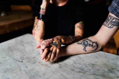 A pair of hands with tattoos holding together, intimacy and friendship concept