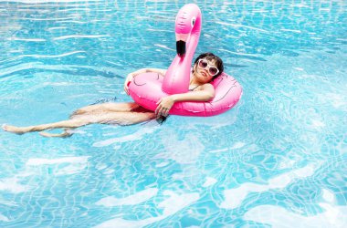 Havuzda şişme şamandıralarla yüzen Asyalı bir kadın.