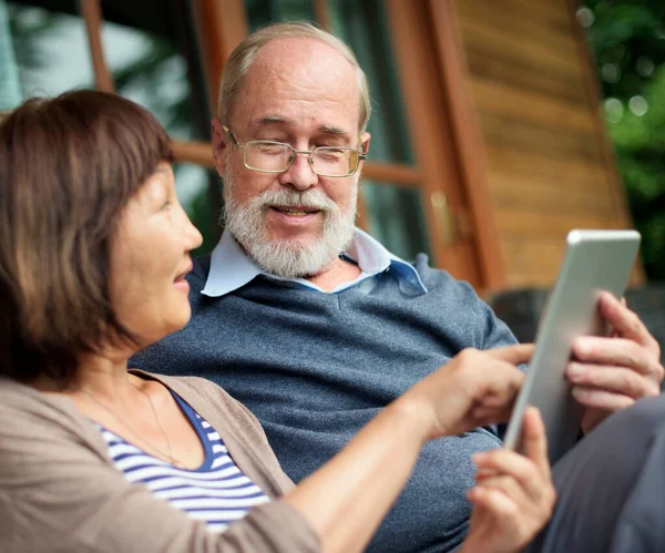 Seniorenpaar Sitzt Vor Einer Holzhütte Und Teilt Sich Ein Tablet — Stockfoto