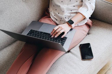 Kanepede yatarken dizüstü bilgisayar kullanan bir kadın.