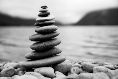 Zen dengeleyici çakıl taşları sisli bir gölün yanında.
