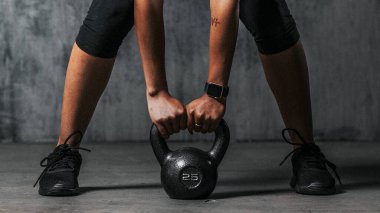 Sportif kadın bir su ısıtıcısını kaldırmaya hazırlanıyor.