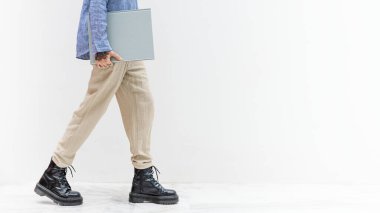 Dövmeli kadın gri bir kitapla yürüyor.