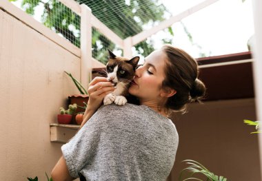 Kucağında kedisini öpen kadın