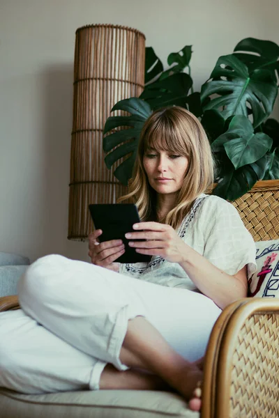 Woman reading an e-book on a digital tablet  during coronavirus quarantine