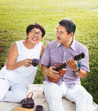 Yaşlı Asyalı çift parkta müzik yapıyor.