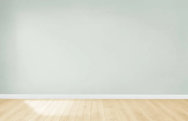 Light green wall in an empty room with a wooden floor