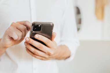 İş adamı sosyal medya hesabını ve mesajlarını telefonla kontrol ediyor.
