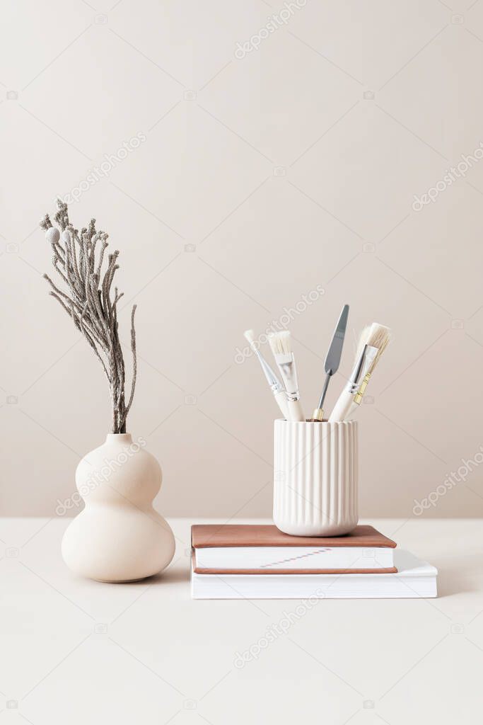 Minimal workspace with paint brushes and a vase