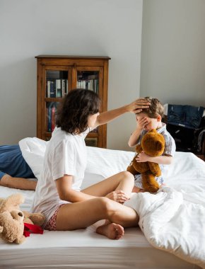 Anne hasta çocuğa yatakta bakıyor.