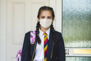 Kız maske takıyor ve okula normal bir şekilde gidiyor.