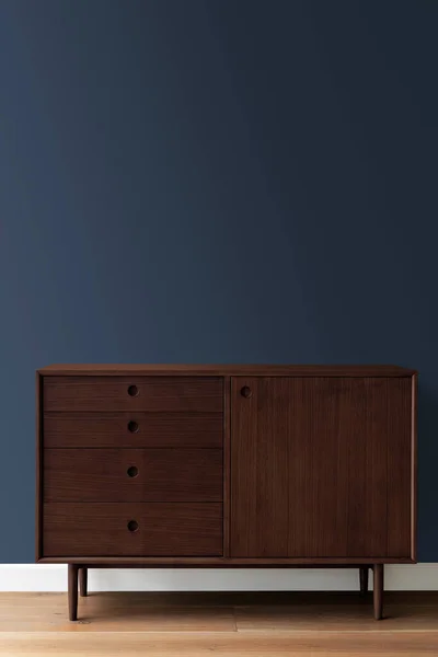 Mid century modern wood cabinet by a blue wall