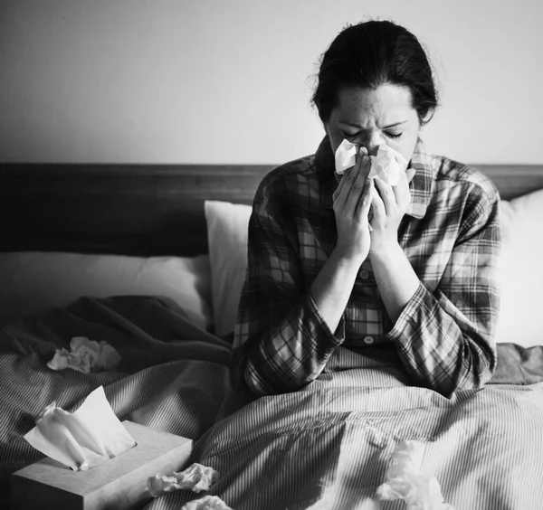 一个生病的女人在床上打喷嚏 — 图库照片