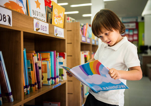 Boy reading  book at a school library