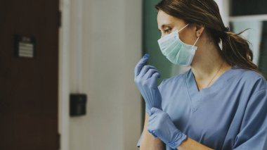 Doktor, koronavirüs kirlenmesini önlemek için eldiven takıyor.