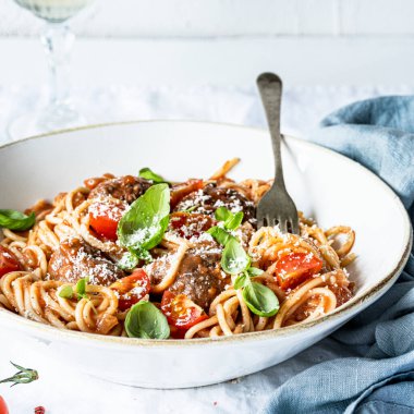 Domates soslu spagetti köftesi üzerine parmesan ve fesleğen yemeği fotoğrafçılığı.