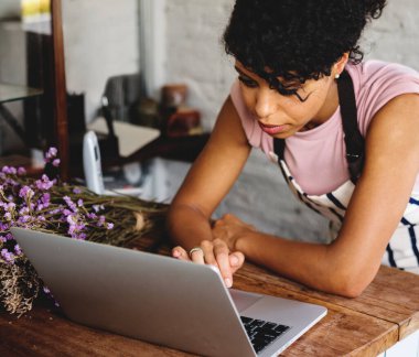 Çiçekçide bilgisayarla çalışan bir kadın.