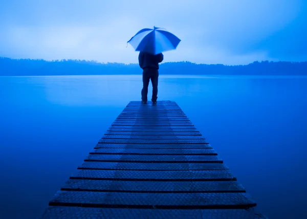 Uomo con un ombrello sul molo — Foto Stock