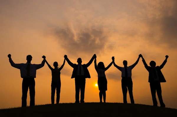 Silhouetten von Menschen, die bei Sonnenuntergang gewinnen — Stockfoto