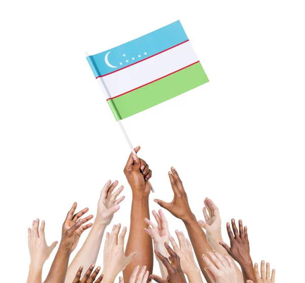 Mänskliga handen håller uzbekistan flagga — Stockfoto