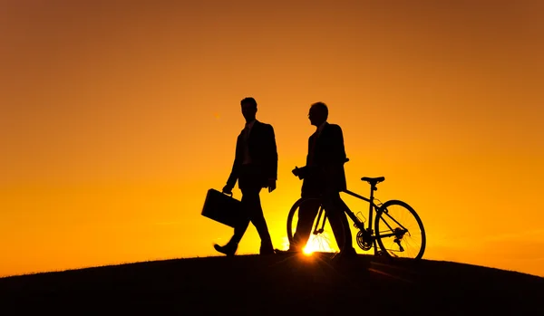 Empresários com bicicleta na colina ao pôr do sol — Fotografia de Stock