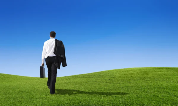 Businessman walking on hill — Stock Photo, Image