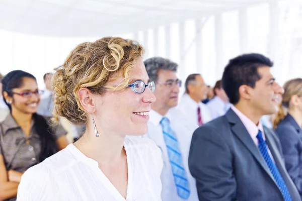 Mulher de negócios sorrindo entre os outros empresários — Fotografia de Stock