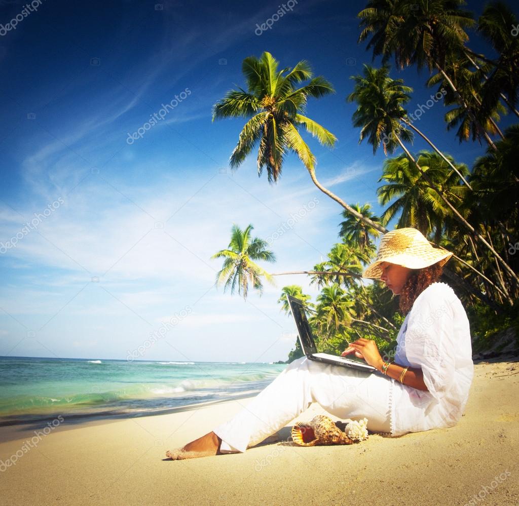 Woman with laptop on beach.