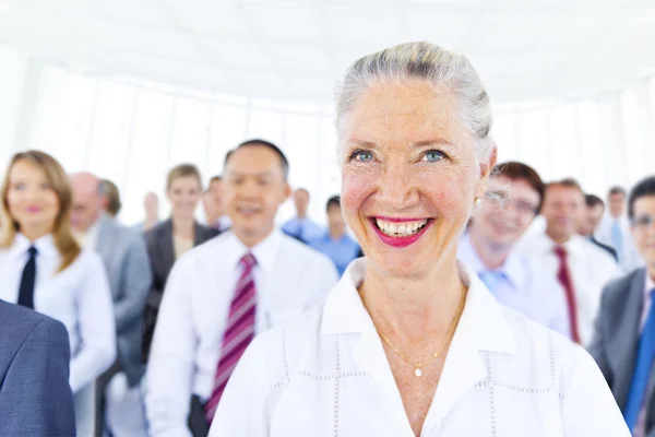 Donna d'affari sorridente tra gli altri uomini d'affari — Foto Stock