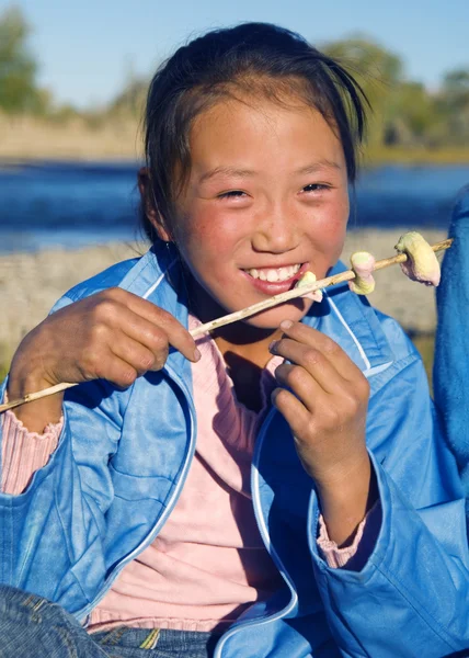 Девушка ест жареный зефир на открытом воздухе — стоковое фото