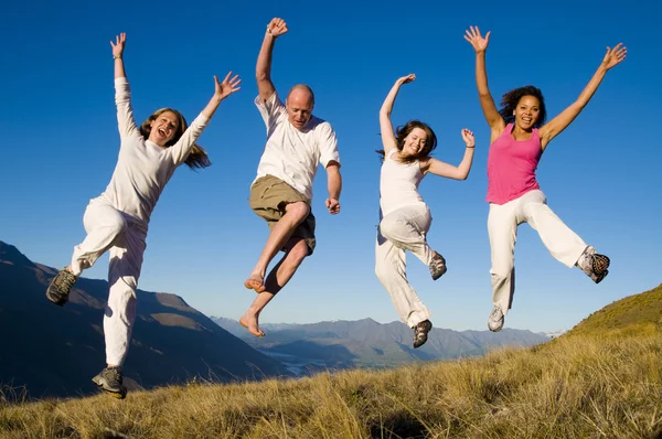 Young people jumping in field — Stock Photo, Image