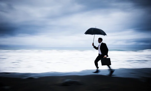 Empresário preocupado correndo pela praia — стокове фото
