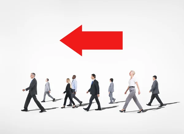 Business people walking under red arrow — Stock Photo, Image