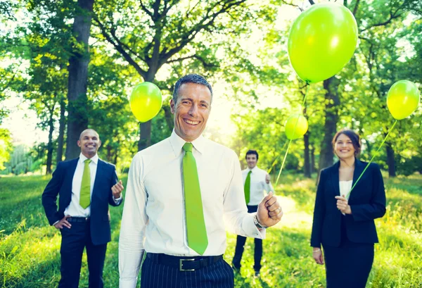 Business people holding green balloons