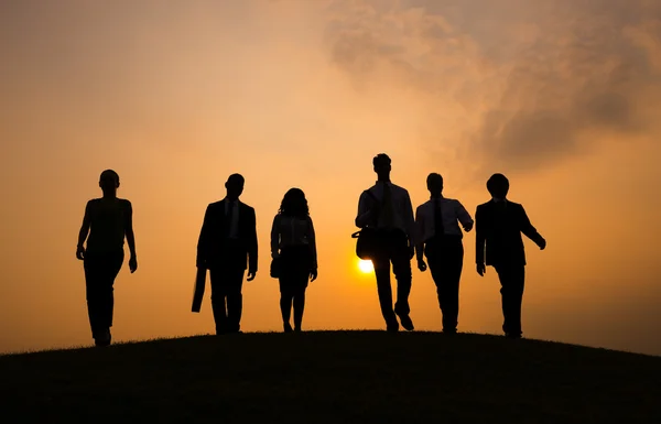 Siluetas de personas caminando al atardecer —  Fotos de Stock