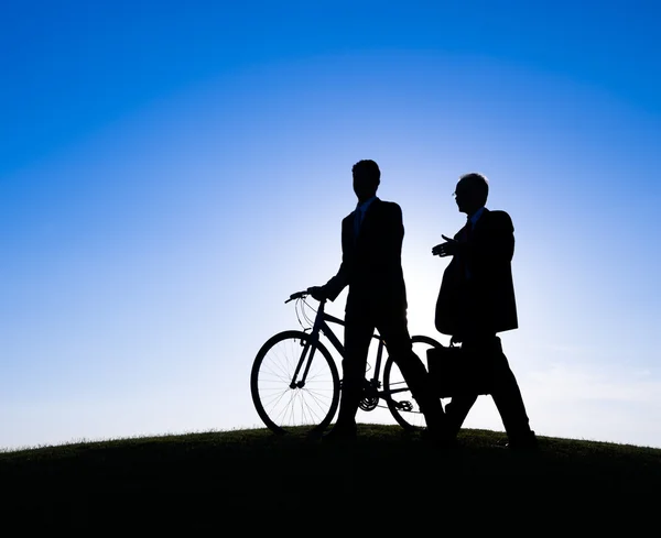 Businessmen walking with bicycle along the hill — Stock Photo, Image