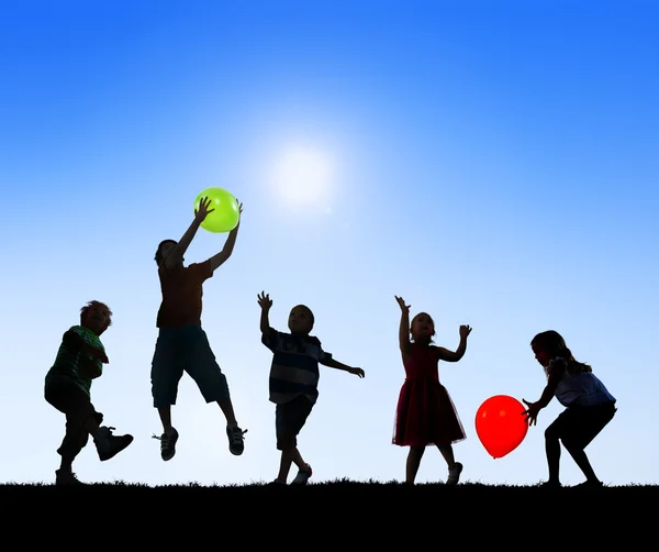 Silhouetten von Kindern, die mit Luftballons spielen — Stockfoto