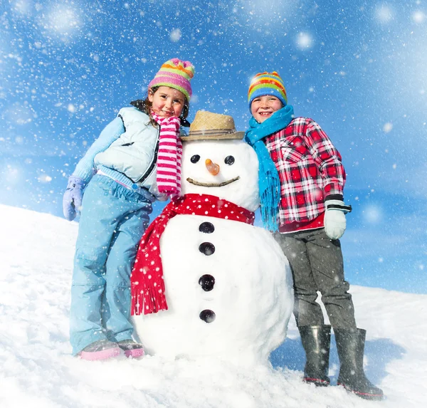 Niños divirtiéndose con muñeco de nieve — Foto de Stock