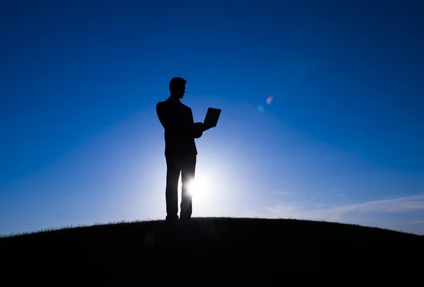 Businessman using laptop on hill — Stock Photo, Image