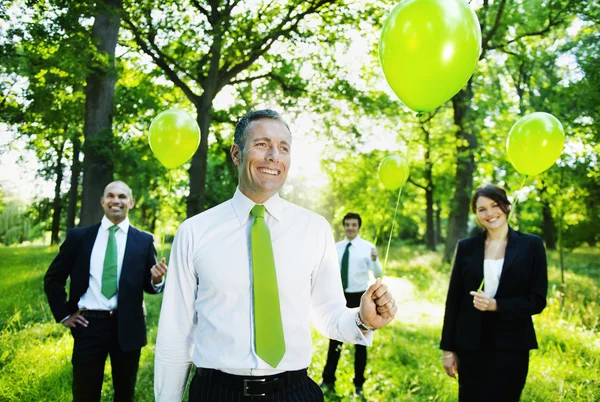 Business people holding green balloons — Stock Photo, Image
