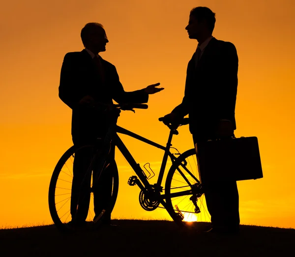 Ondernemers met fiets op heuvel bij zonsondergang — Stockfoto