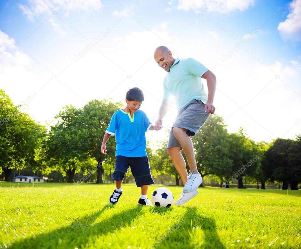 Boy playing soccer with father