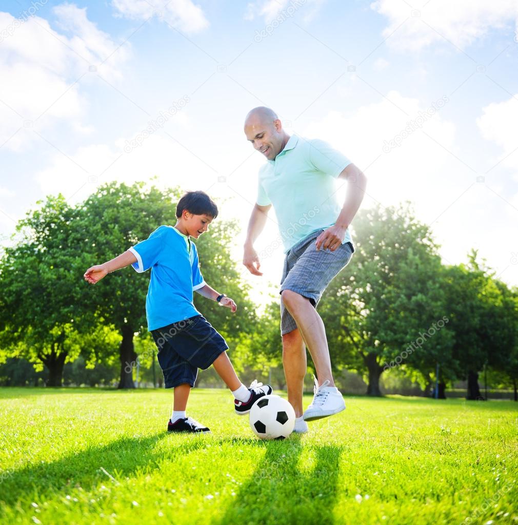 Boy playing soccer with father