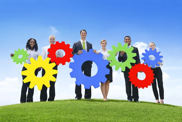 Business people holding colored gears — Stock Photo, Image