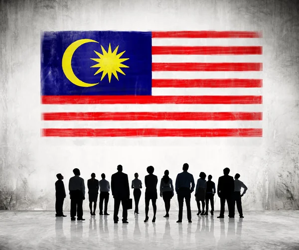 Obchodní lidé při pohledu na malajské vlajky — Stock fotografie