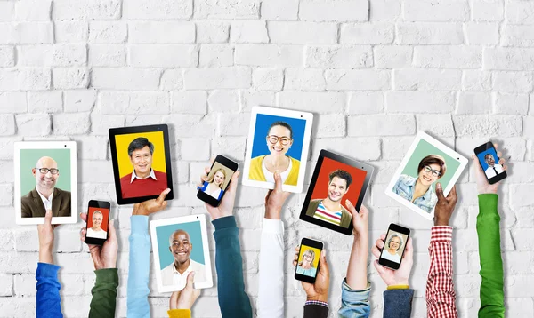 Handen met digitale apparaten met gezichten van mensen — Stockfoto